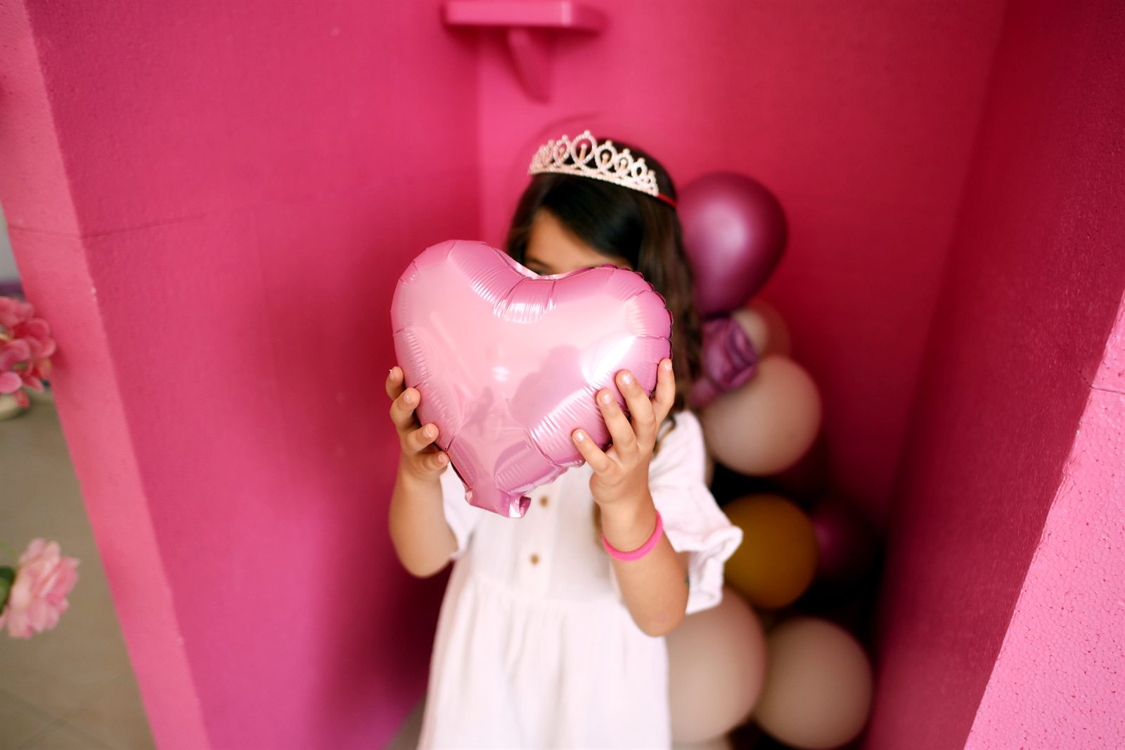Roze balon u obliku srca ispred zida od balona